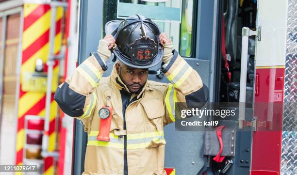 firefighter putting on fire protection suit and helmet - firefighter getting dressed stock pictures, royalty-free photos & images