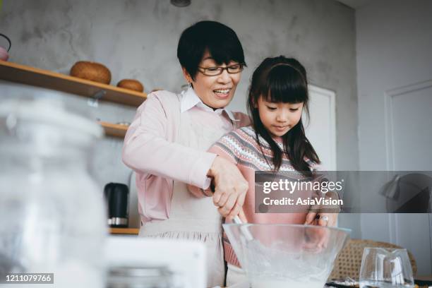 joyful little girl having fun making cookies with her grandmother together in the kitchen - hong kong grandmother stock pictures, royalty-free photos & images