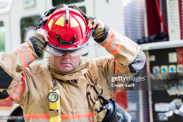 firefighter in fire protection suit putting on helmet - firefighter getting dressed stock pictures, royalty-free photos & images