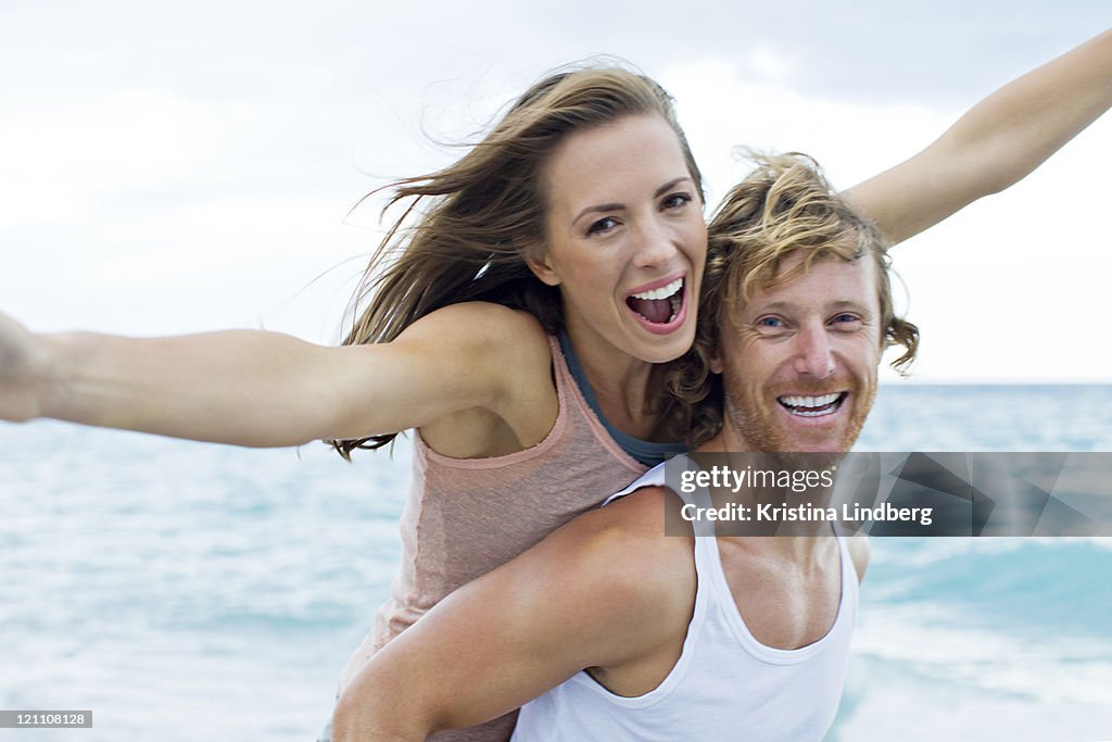 Couple having fun by the sea, looking to camera.