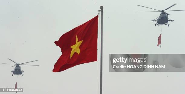 Helicopters carrying communist and national flags fly over during a military parade held in front of late president Ho Chi Minh's mausoleum on...