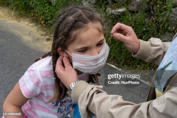 Mother helps her daughter put on a mask the first day that children are released after 42 days of confinement, during the mandatory quarantine...