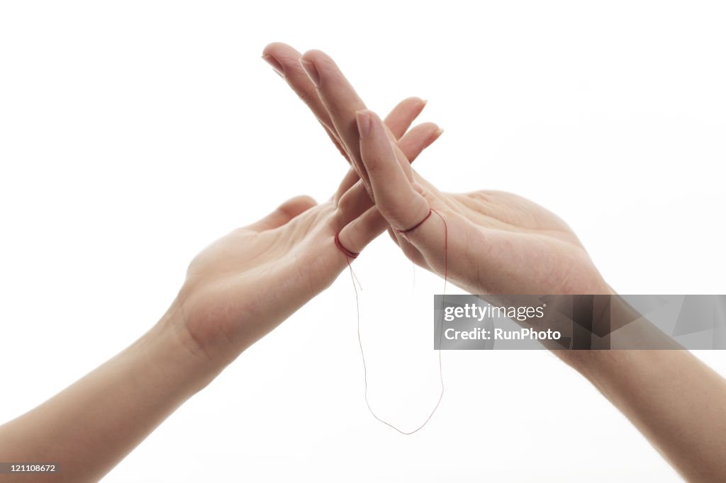 Woman and man connected by red thread tied pinkies