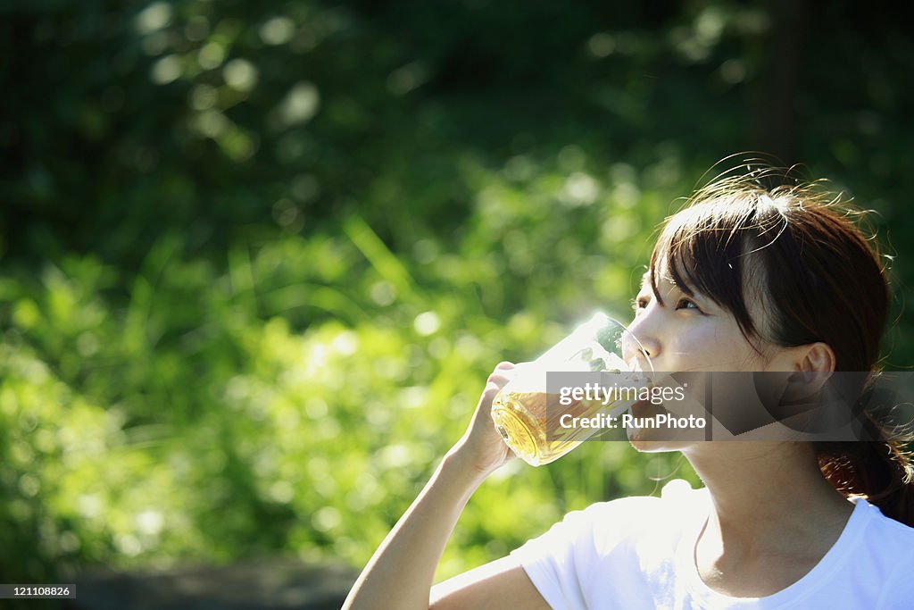 Young woman drinking beer outside