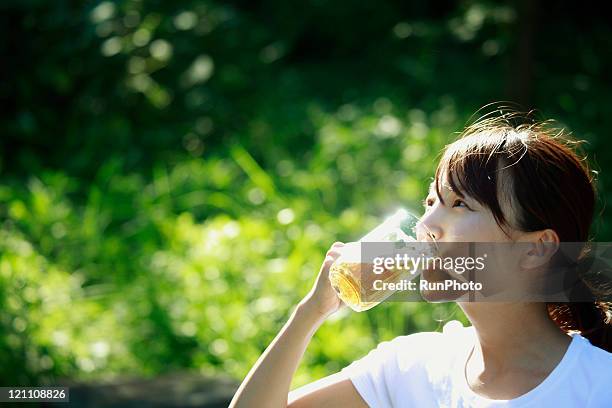 young woman drinking beer outside - drink ストックフォトと画像