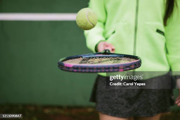 female teenager holding tennis ball and racket - schlägersport stock-fotos und bilder