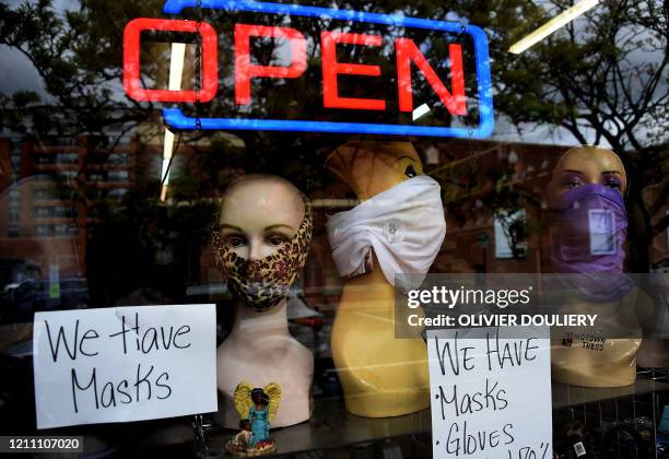 Mannequin heads wear masks in the window of a small boutique advertising availability of masks, gloves, and other pandemic necessities amid the...