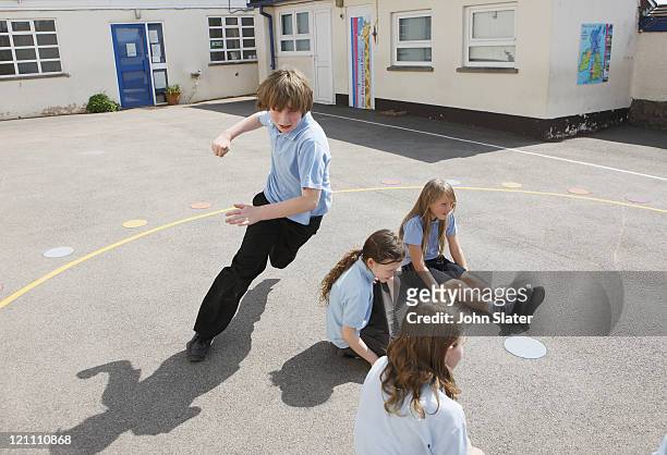 school children playing in playground - school uniforms stock-fotos und bilder