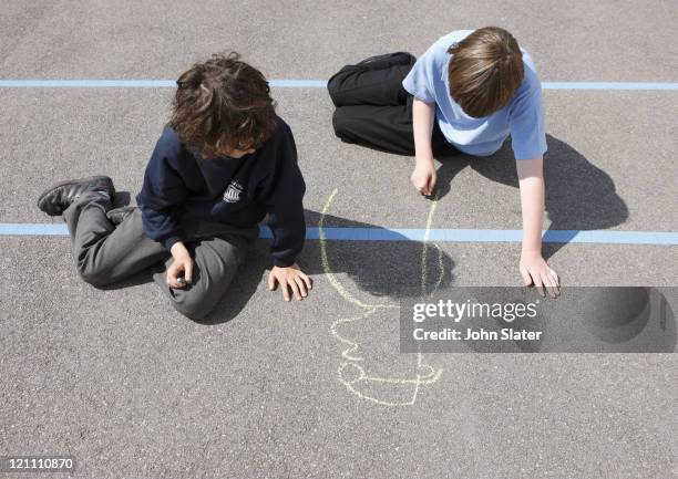 school children drawing with chalk in playground