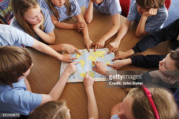 group of schoolchildren using atlas together - physical geography stock-fotos und bilder