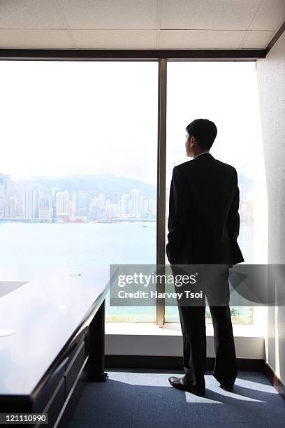 businessman looking out office window, rear view - homens de idade mediana imagens e fotografias de stock
