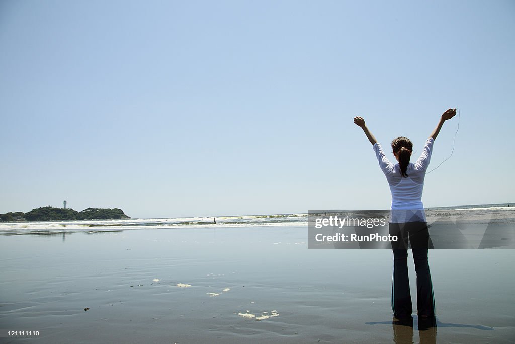 Young woman listening to music on the beach