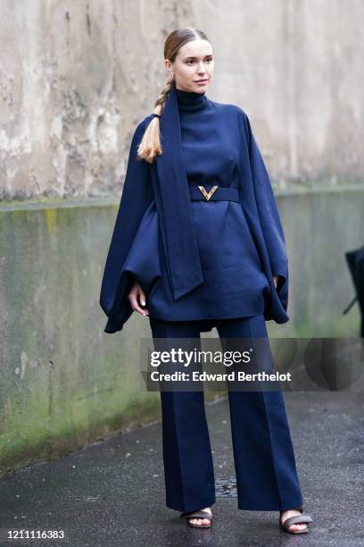 Pernille Teibaek wears a navy blue turtleneck pullover with pagoda large sleeves, a belt, flared pants, sandals, outside Valentino, during Paris...