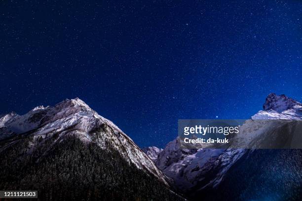 majestic mountains landscape at night against clear sky with stars - royal blue stock pictures, royalty-free photos & images