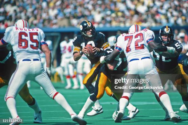 Quarterback Cliff Stoudt of the Pittsburgh Steelers drops back to pass as offensive linemen Steve Courson and Mike Webster block defensive lineman...