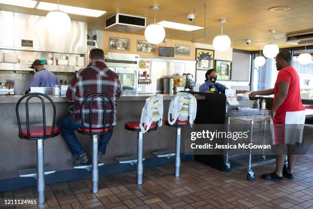 With some seats and booths marked off to adhere to social distancing protocol, customers enjoy dine-in and take-out service at a Waffle House on...