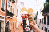 Beautiful and delicious italian gelato in waffle cone in front of streets and bridges of Venice.