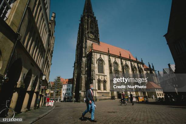 A man wearing face mask walks past the dom square of Munster as Germany makes compulsory wearing face mask on a train, bus and also shops, in...