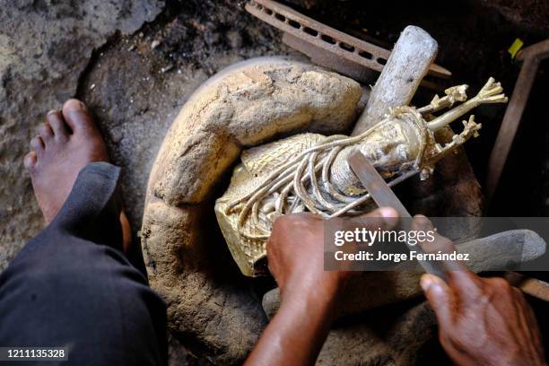 Craftsman finishing polishing the last details of a bronze statuette made using the technique of lost wax casting, used in the kingdom of Benin...