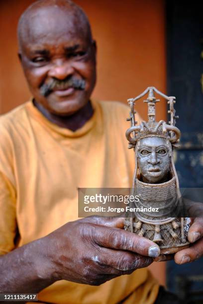 Artisan holding a wax figurine used as a model to make the mold used in the traditional lost wax casting technique, used in the kingdom of Benin...
