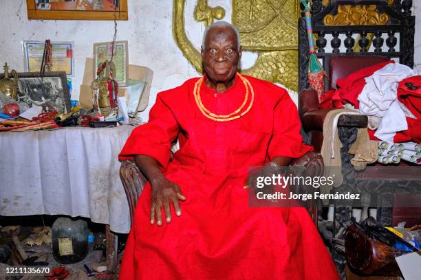 Portrait of an old traditional priest with various fetishes and amulets in his Benin City home.