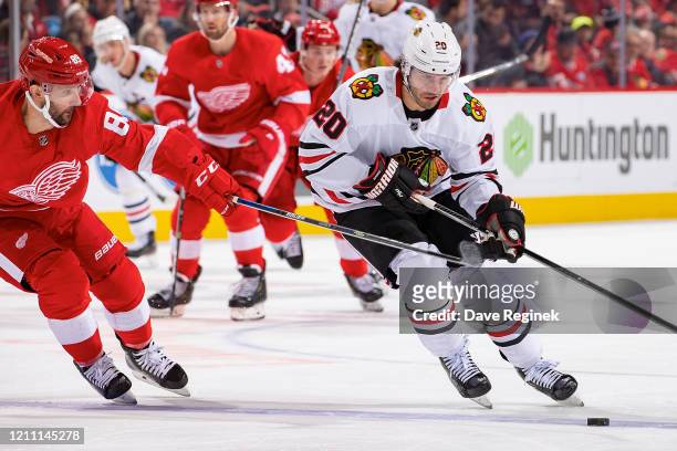 Brandon Saad of the Chicago Blackhawks protects the puck from Sam Gagner of the Detroit Red Wings during an NHL game at Little Caesars Arena on March...