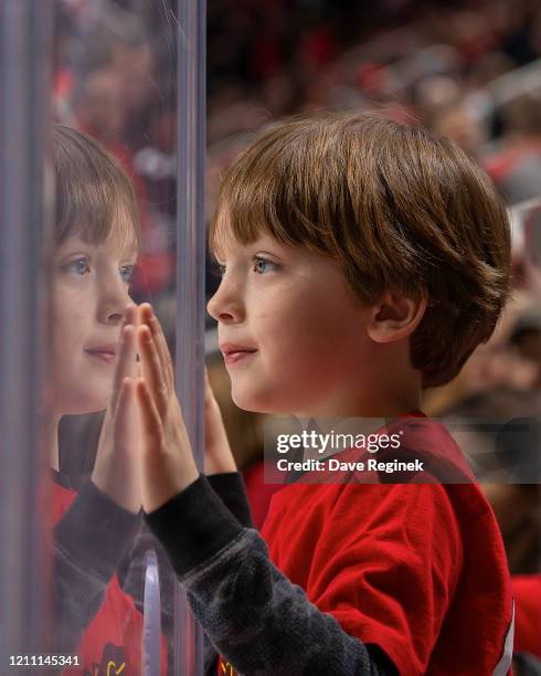 Young fan looks thru the glass during an NHL game between the Detroit Red Wings and the Chicago Blackhawks at Little Caesars Arena on March 6, 2020...