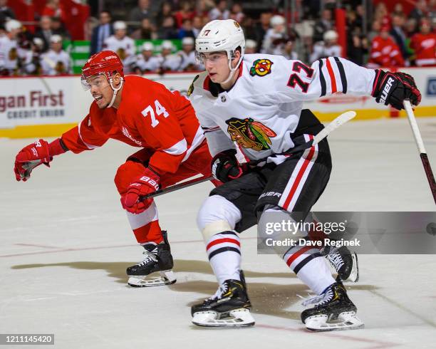 Madison Bowey of the Detroit Red Wings defends against Kirby Dach of the Chicago Blackhawks during an NHL game at Little Caesars Arena on March 6,...