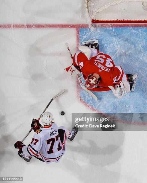 Jonathan Bernier of the Detroit Red Wings makes a save as Kirby Dach of the Chicago Blackhawks looks for the rebound during an NHL game at Little...