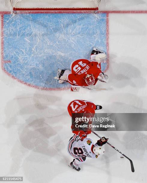 Jonathan Bernier of the Detroit Red Wings reacts to a shot as teammate Filip Hronek battles for position with Ryan Carpenter of the Chicago...