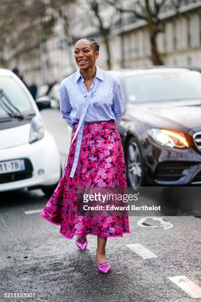 Actress Naomi Ackie wears a mauve shirt, a red and pink floral print skirt, pink pointy Valentino shoes, outside Valentino, during Paris Fashion Week...