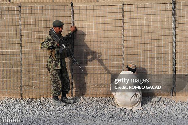 An Afghan National Army soldier guards two suspected Taliban detainees at the Combat Outpost Kandalay in southern Afghan province of Kandahar on...