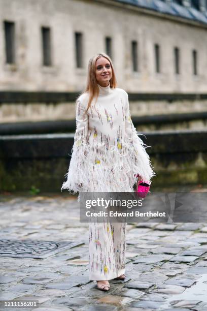 Charlotte Groeneveld wears a white turtleneck pullover with fringes, flared pants, a pink bag, pointy shoes, outside Valentino, during Paris Fashion...