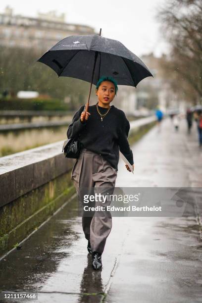 Margaret Zhang wears an oversized pullover, a necklace, gray flowing pants, black leather pointy boots, a bag, outside Valentino, during Paris...