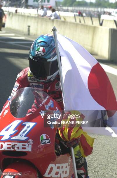 Le Japonais Youichi Ui rentre, le 14 mai 2000 au paddock, un drapeau japonais à la main après sa victoire dans l'épreuve de la catégorie des 125CC du...