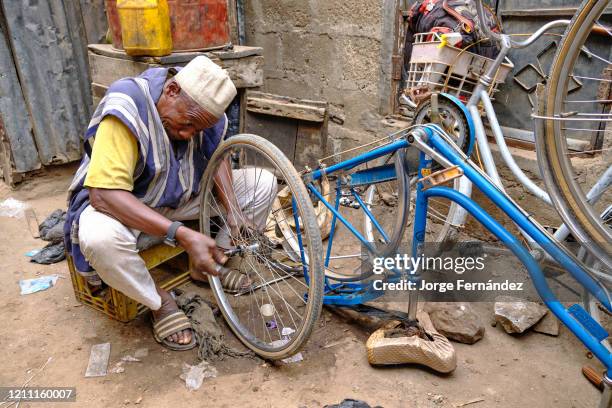 Man repairing bicycle on the streets of the Kano market.