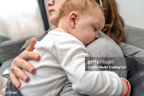 mother tapping baby boy on his back to burp - tap forehead stock pictures, royalty-free photos & images