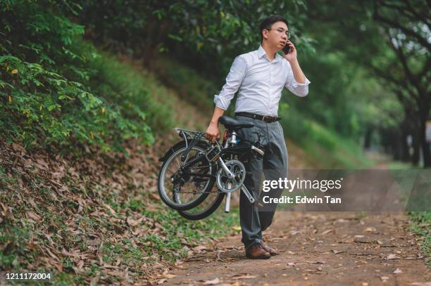 an asian chinese white collar worker executive with folding bicycle for commuting talking thru his phone - foldable stock pictures, royalty-free photos & images