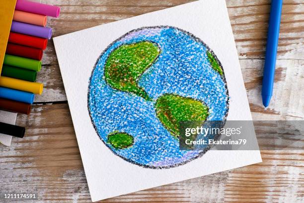 Hand drawing Planet Earth with wax crayons on wooden background.