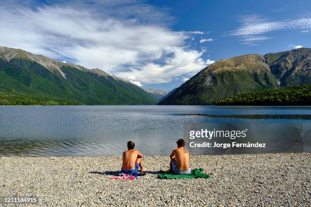 Two young men sunbathing at the shore of Lake Rotoiti, Nelson Lakes National Park.