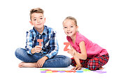 Cute children playing with large colorful alphabet letters on white background. Kids speech therapy concept. Speech impediment, logopedy, dyslexia background.