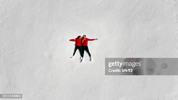 aerial view of couple having fun making snow angel. - snow directly above stock pictures, royalty-free photos & images