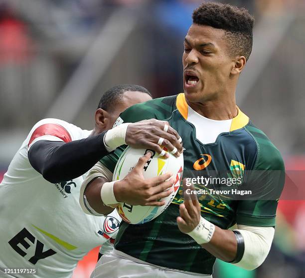 Angelo Davids of South Africa carries the ball in front of Perry Baker of USA during their rugby sevens match at BC Place on March 08, 2020 in...