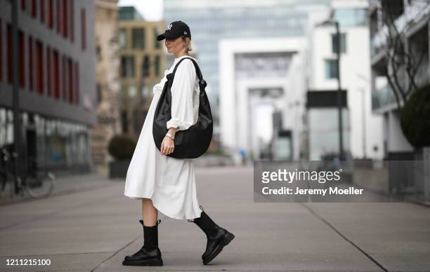 Kathrin Bommann wearing Pixie Shop dress, Bottega Veneta boots, Frankie Shop bag and, New Era cap on March 07, 2020 in Cologne, Germany.