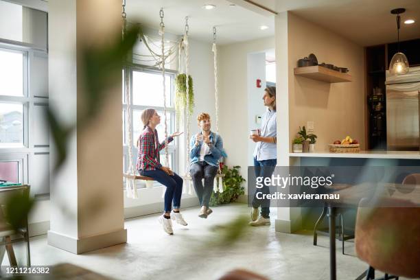 casual businesspeople talking on break in coworking office - coworking spaces stock pictures, royalty-free photos & images