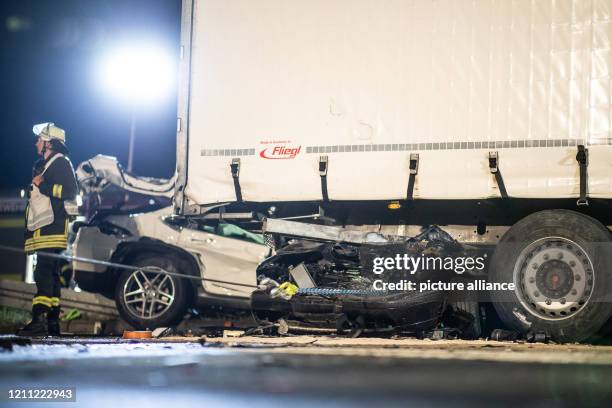 April 2020, North Rhine-Westphalia, Castrop-Rauxel: A completely destroyed car lies crosswise under a truck trailer. Three people have died in a...