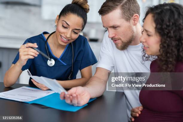 attractive female practitioner shows expecting couple ultrasound sonogram. - young adult with doctor stock pictures, royalty-free photos & images