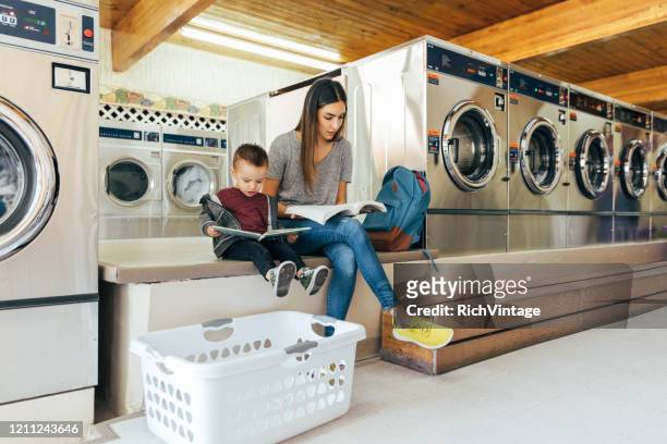 estudiante padre estudiando en lavandería - laundromat fotografías e imágenes de stock