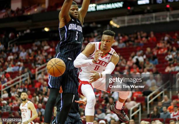 Russell Westbrook of the Houston Rockets passes the ball under the basket while defended by Mo Bamba of the Orlando Magic in the second half at...