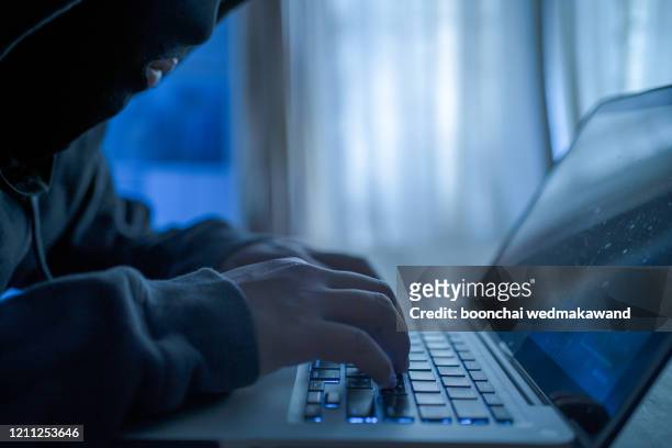 cropped shot of an unidentifiable hacker using a laptop - corporate theft photos et images de collection